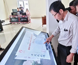 Đại biểu trải nghiệm xem triển lãm trực tuyến tại Bình Định trên màn hình cảm ứng - Ảnh: T.H